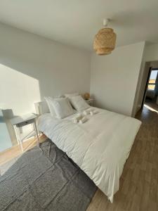 uma cama branca num quarto branco com uma mesa em Modern and bright apartment near Paris em La Courneuve