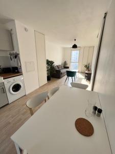 uma cozinha e sala de estar com uma mesa branca e cadeiras em Modern and bright apartment near Paris em La Courneuve