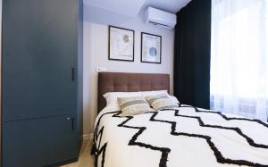 Schlafzimmer mit einem Bett mit einer schwarzen und weißen Bettdecke in der Unterkunft MYFREEDOM Апартаменти Залізничний Вокзал in Kiew