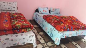 a bedroom with two beds and a bed with a blanket at Prince Homestay & Restaurant in Rudraprayāg