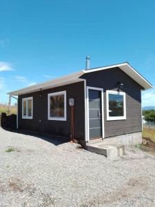 una pequeña casa negra sentada encima de un lote de grava en Cabañas Kápenken, #2, en Coyhaique