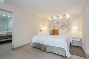 a bedroom with a large white bed and a bathroom at Sugar Bay Barbados - All Inclusive in Bridgetown