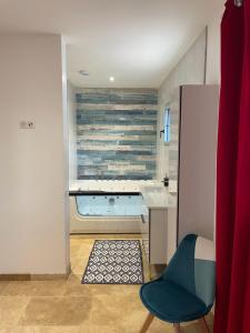 eine Küche mit einer Badewanne und einem Stuhl in einem Zimmer in der Unterkunft Gite de L'Enclos in Lavardens