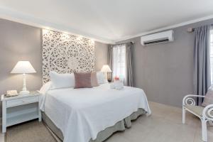 a bedroom with a white bed and a chair at Sugar Bay Barbados - All Inclusive in Bridgetown