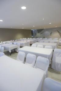 TRYP by Wyndham Chetumal في تْشيتومال: غرفة مليئة بالطاولات البيضاء والكراسي البيضاء