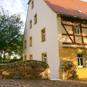 a white house with a stone fence in front of it at Fährmannshof im Elbtal in Klipphausen