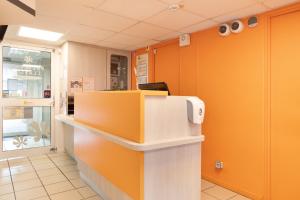 ein Büro mit orangefarbenen Wänden und einer Rezeption in der Unterkunft Premiere Classe Meaux Nanteuil Les Meaux in Nanteuil-lès-Meaux