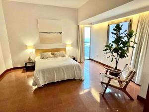 um quarto com uma cama e um vaso de plantas em Luxury Beachfront Apartment Las Canteras em Las Palmas de Gran Canaria