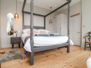 a bedroom with a canopy bed with a wooden floor at Treveddoe Farmhouse in Bodmin