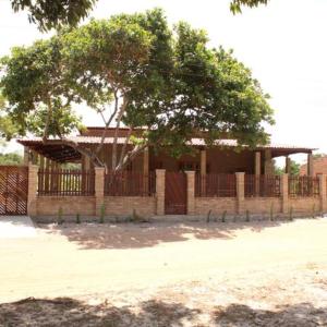a building with a fence and a tree at Casa ecológica próx à Lagoa Azul - Jericoacoara in Cruz