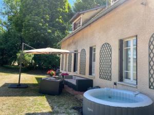 einen Whirlpool vor einem Haus mit Sonnenschirm in der Unterkunft LE PARC in Coulanges-sur-Yonne