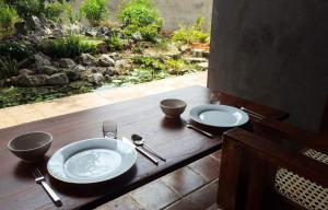 a wooden table with two plates and silver utensils at Takimi Mini Villa in Wellawaya