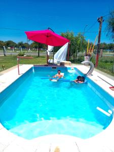 Dos personas en una piscina con sombrilla en LA CABAÑA en Termas de Río Hondo