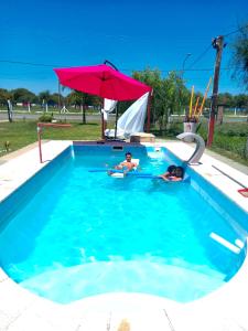 two people in a swimming pool with an umbrella at LA CABAÑA in Termas de Río Hondo