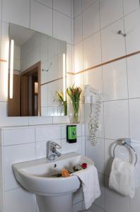 Baño blanco con lavabo y espejo en Friends Hotel Kerpen, en Kerpen
