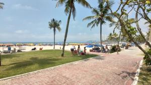 een groep mensen op het strand met palmbomen bij Enseada Guarujá Ap214 in Guarujá