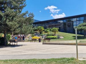 a building with benches and people walking in front of it at L' Oteni in Publier