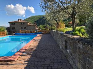 una piscina con una pared de piedra junto a una casa en Appartamento La Loggetta, en Corgna