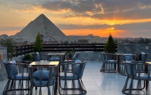 Kemet Boutique Hotel في القاهرة: فناء به طاولات وكراسي والأهرامات