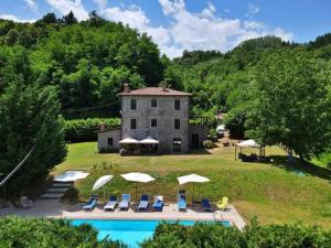 una casa con piscina y sillas y un edificio en Villa Casa di Pietra en el norte de Lucca, Toscana, en Camporgiano