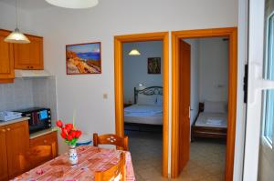 a kitchen with a table and a bedroom with a bed at Lagos Studios & Apartments in Palekastron