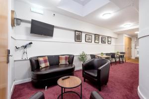 a waiting room with black leather furniture and a flat screen tv at SMITH PLACE HOTEL in Edinburgh