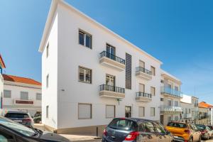 a white building with cars parked in front of it at Sueños Del Mar in Nazaré