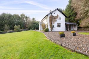 a white house with a large lawn in front of it at Strathendrick House Magnificent property with Garden in Drymen