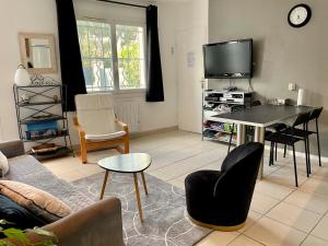 a living room with a table and a tv at Key Largo villa 2p avec pkg clim grande terrasse avec jacuzzi proche port et plage in Bandol