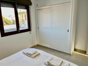 1 cama blanca con 2 toallas plegables y una ventana en Apartamento Cala Ratjada. Recién reformado, en Cala Ratjada 12 fotos más