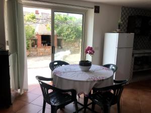 cocina con mesa, sillas y nevera en Villa Ederle en La Maddalena