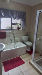 a bathroom with a tub and a toilet and a sink at 8 On Eagle Self Catering Apartment in Umtentweni