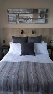 a bed with black and white sheets and pillows at 8 On Eagle Self Catering Apartment in Umtentweni