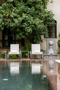 two white chairs sitting next to a swimming pool at Hospes Palacio del Bailio, a Member of Design Hotels in Córdoba
