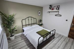 a bedroom with a bed with white sheets and a plant at Manchester, Rusholme, UK with free parking in Manchester