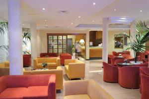 un vestíbulo con mesas y sillas rojas y amarillas en Hotel Conca Verde, en Lignano Sabbiadoro