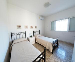 two beds in a bedroom with white walls and a window at Casa tu Nonnu in Ugento