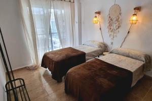 a hotel room with two beds and a window at Piso Vintage Centro Gandía in Gandía