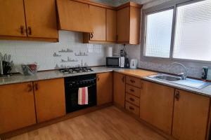 a kitchen with wooden cabinets and a stove and a sink at Piso Vintage Centro Gandía in Gandía