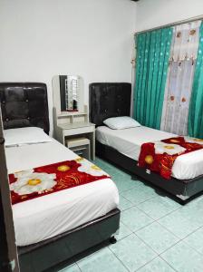 a room with two beds and a table with a mirror at HOMESTAY KARTINI SYARIAH in Bukittinggi