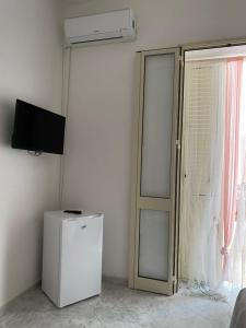 Zimmer mit einem Kühlschrank, einem TV und einem Fenster in der Unterkunft Paste&cannola in Lampedusa