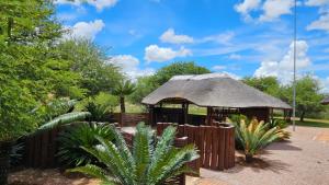 a gazebo with a thatched roof in a garden at Makhato Bush Lodge 48 in Bela-Bela