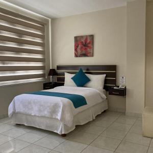um quarto com uma cama grande e almofadas azuis e brancas em Hotel Ceibo Dorado em Portoviejo