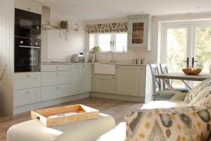 a kitchen with white cabinets and a table at Finwood Green Farm Holiday Cottages-The Calf Shed and The Milk Parlour in Henley in Arden