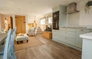 a kitchen with white cabinets and a living room at Finwood Green Farm Holiday Cottages-The Calf Shed and The Milk Parlour in Henley in Arden