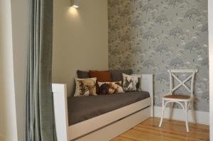 un letto in una stanza con una sedia e una parete di Fernando Pessoa Apartment a Lisbona