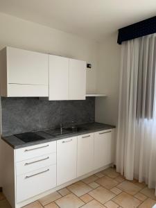 a kitchen with white cabinets and a sink at Hotel Lory Ficarolo in Ficarolo