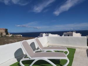 two white chairs sitting on the side of a wall at Casa Agua y Sol I in Poris de Abona