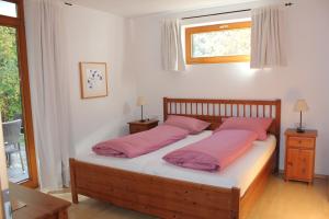 um quarto com uma cama com almofadas cor-de-rosa e uma janela em Ferienwohnungen Almrausch em Oberammergau