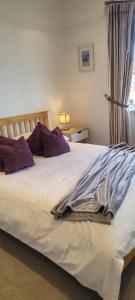 a bedroom with a large white bed with purple pillows at Quiet Terraced House in Bristol